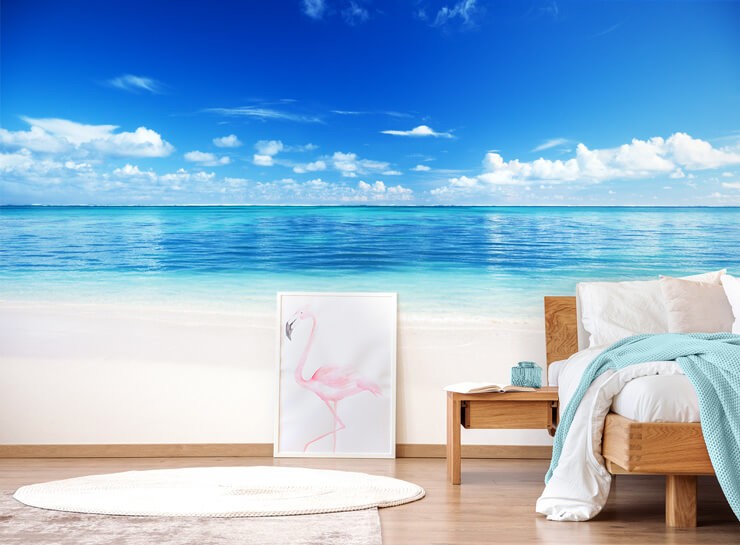 blue ocean and white sands wallpaper in bedroom with wooden bed and flamingo frame
