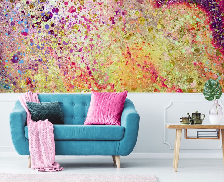Colourful wallpaper mural of speckled texture with white panels, a light blue sofa and pink cushions