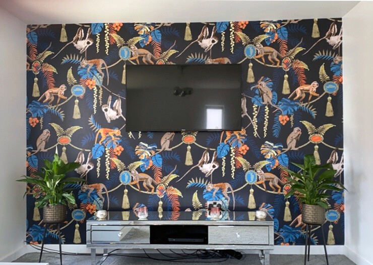 navy monkey vintage wallpaper on wall behind tv and console
