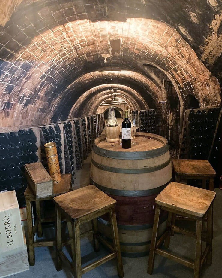 Interior with a 3D wallpaper of a wine cellar in a bar with rustic furniture