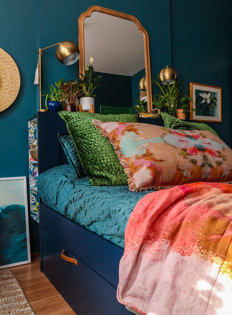 Dark bedroom with varying colours of bedsheets with a blue wall