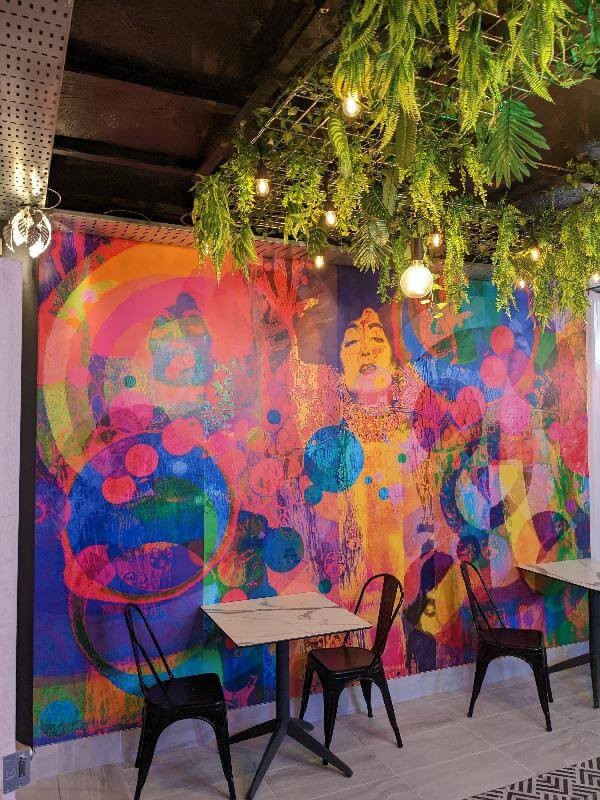 Bar interior with a colourful wall mural with marble tables and black chairs