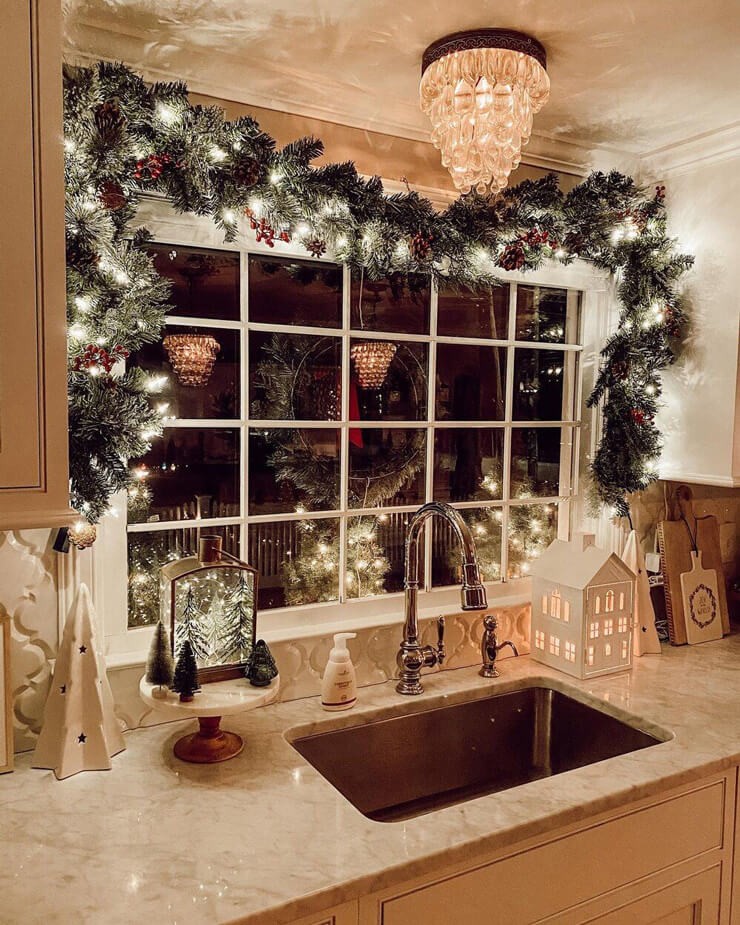 Beige kitchen with a window that has warm white lights and a green wreath