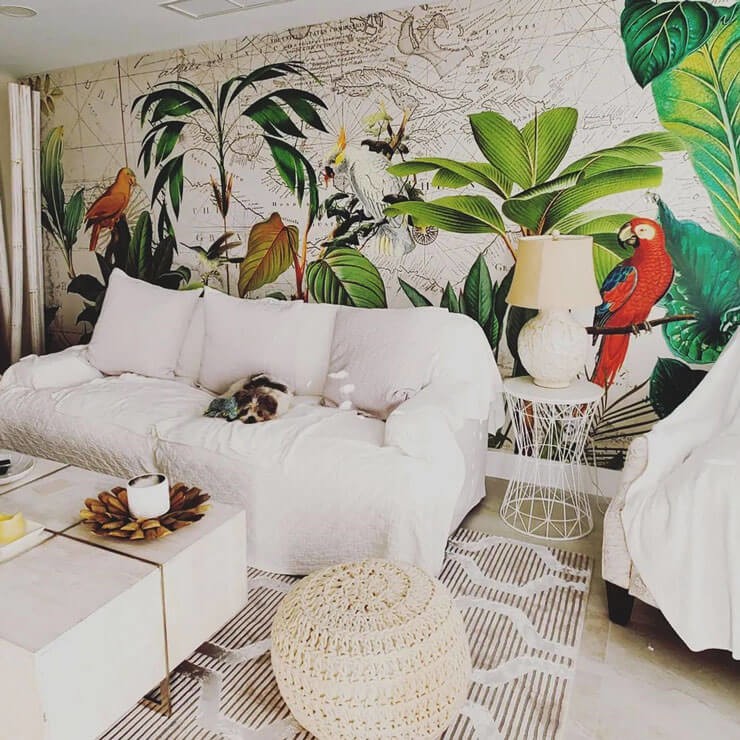 Neutral white living room with a white sofa, rattan accessories and a jungle wallpaper